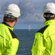 Two workers look at wind turbines as viewed from the Modular Offshore Grid in the North Sea off of the Belgian coast.